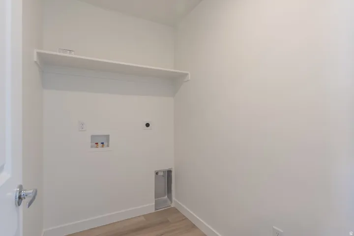 Laundry area with a built-in shelf, plumbing hookups, and wood-finish flooring