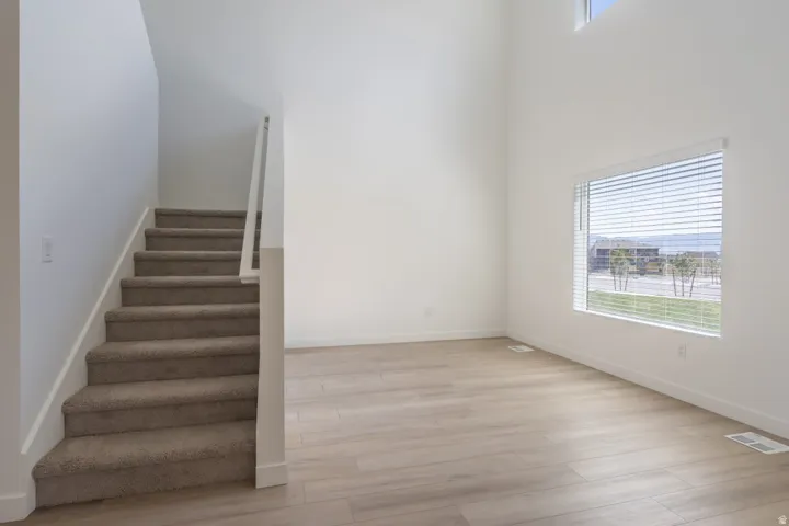 High ceilings with an upper window, wood-finish flooring, and a large window with horizontal blinds