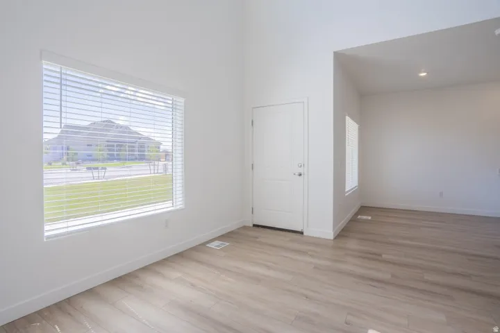 Vaulted ceilings with recessed lighting, wood-finish flooring, and a paneled entry door