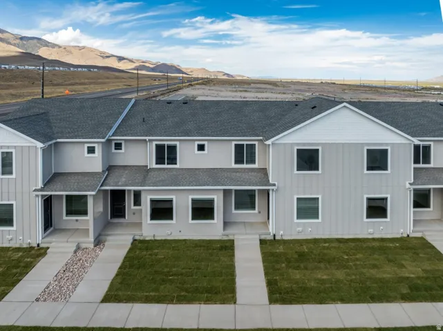 Contemporary townhome exterior with light gray siding, dark gray shingle roof, and white trim windows