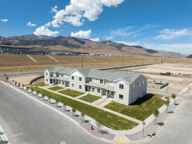 Modern farmhouse-style residential complex featuring clean-lined white exterior with multiple gabled rooflines, manicured lawn with mature landscaping, and paved driveway with designated parking