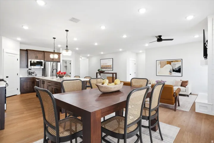 Open-concept interior featuring wood-finish flooring, recessed lighting, a modern kitchen with dark wood cabinetry, a central island, and stainless steel appliances