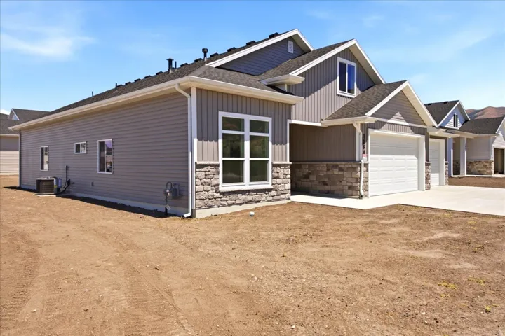 Contemporary exterior featuring horizontal and vertical siding, stone accents, multiple window styles, and an attached two-car garage