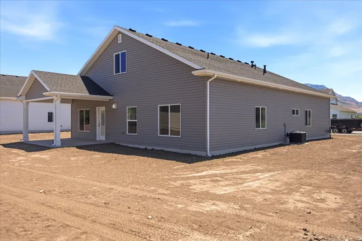 Spacious backyard featuring a covered patio, multiple windows, gray horizontal siding, and a gabled roofline