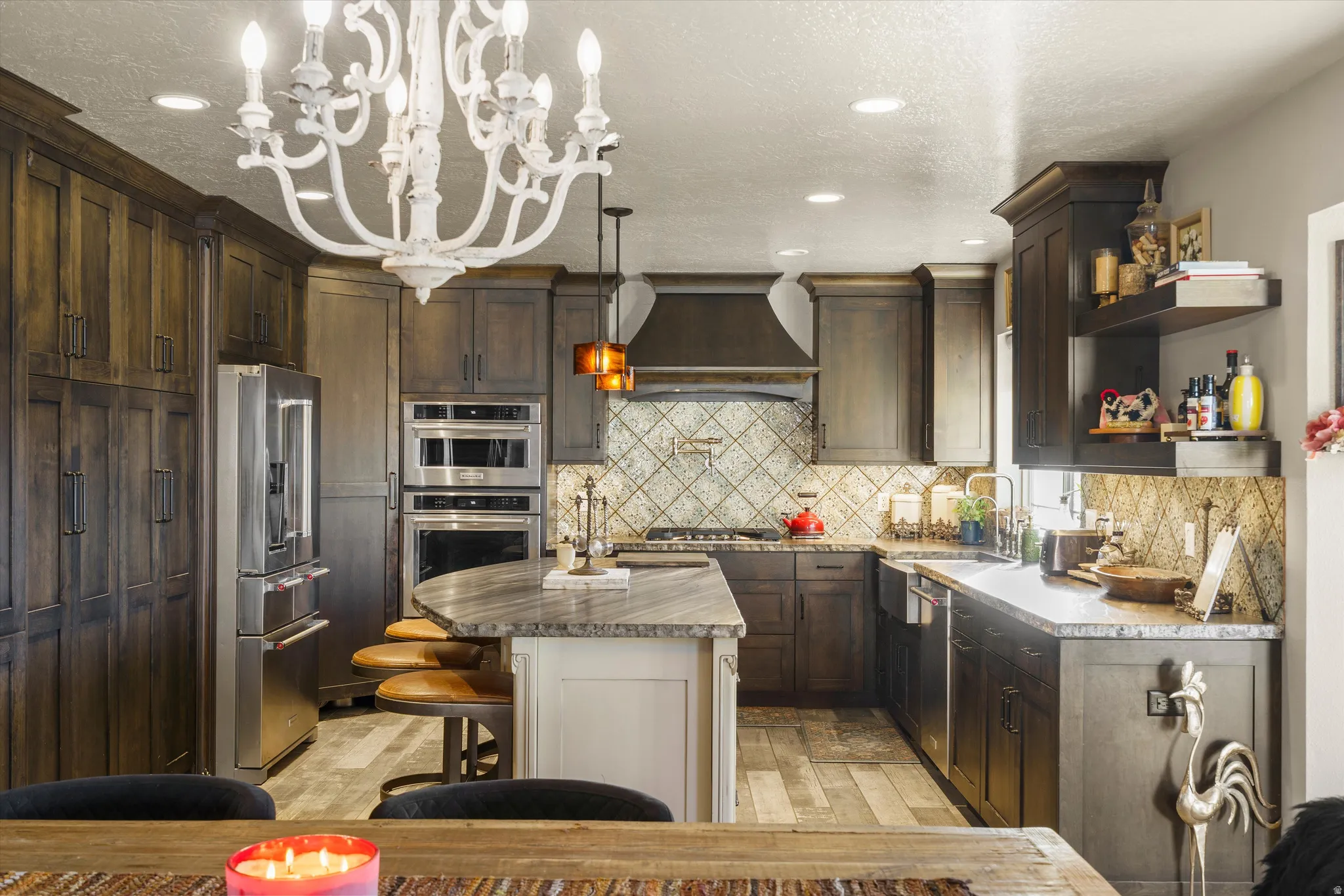 Spacious kitchen featuring dark wood-finish cabinetry, stainless steel appliances, and a central island with a stone-finish countertop