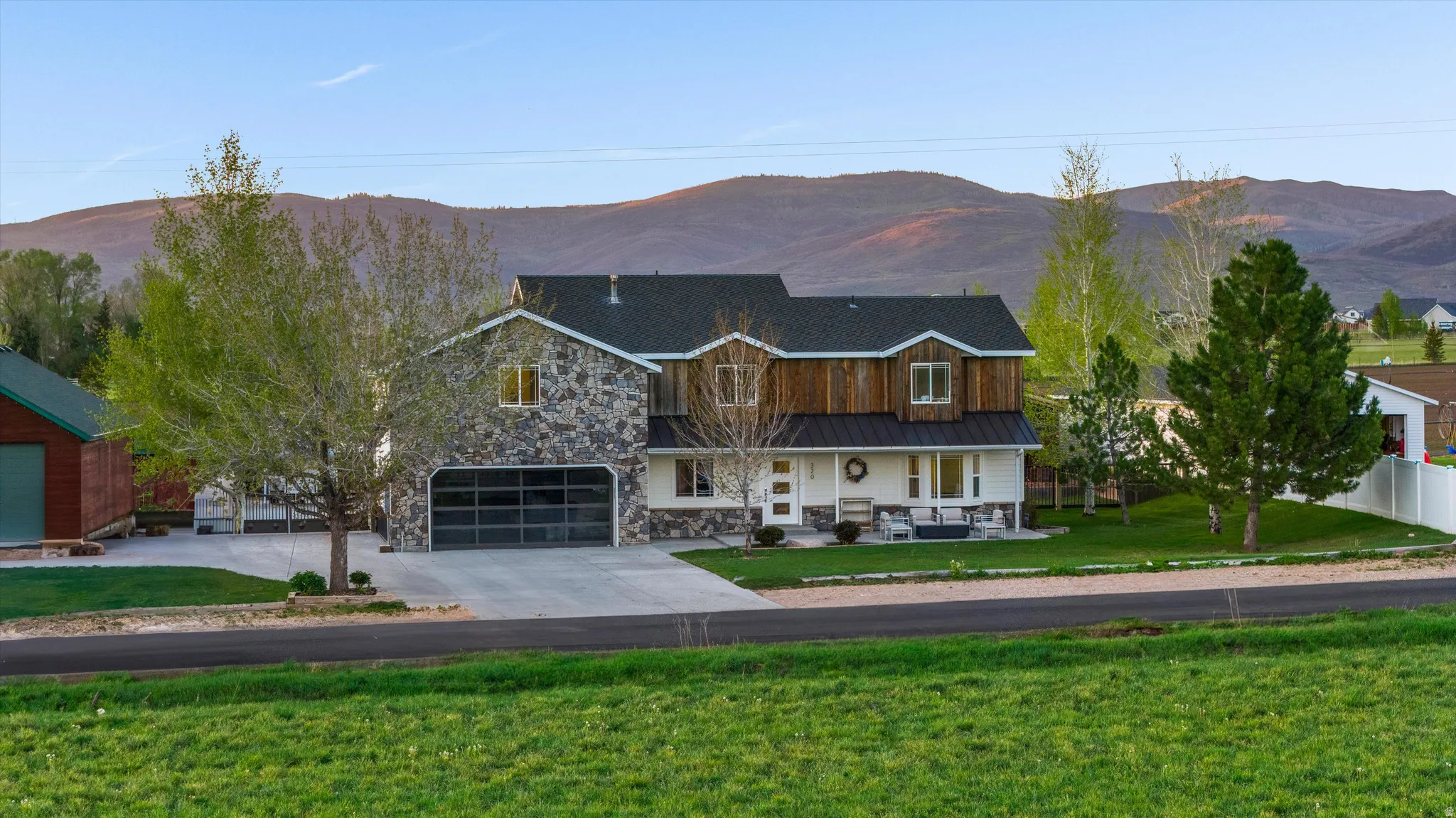 Stone and wood-sided residence featuring a two-car garage with a frosted glass door, a covered porch, and a dormer window