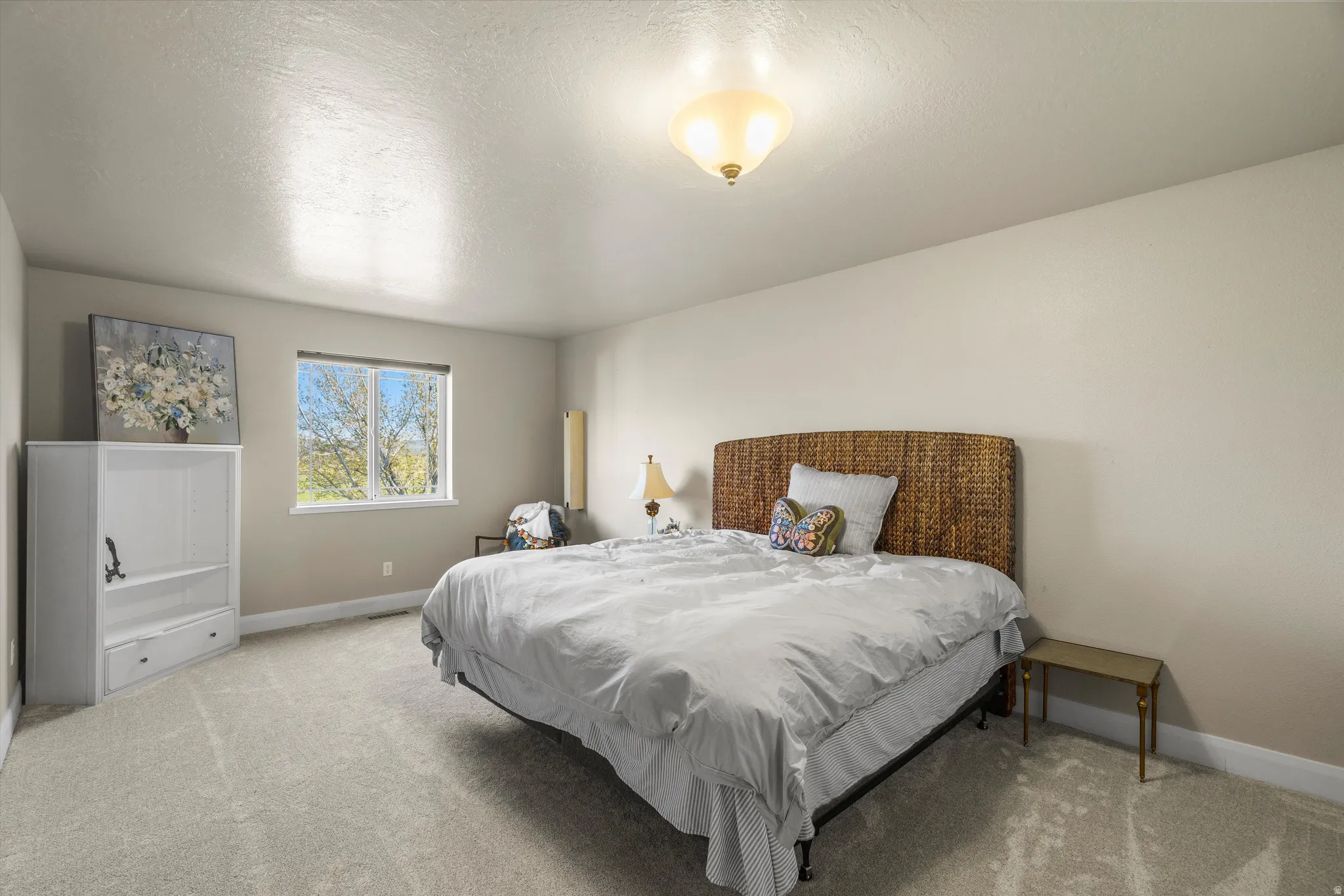 Spacious room featuring neutral carpeting, a large window, and a ceiling-mounted light fixture