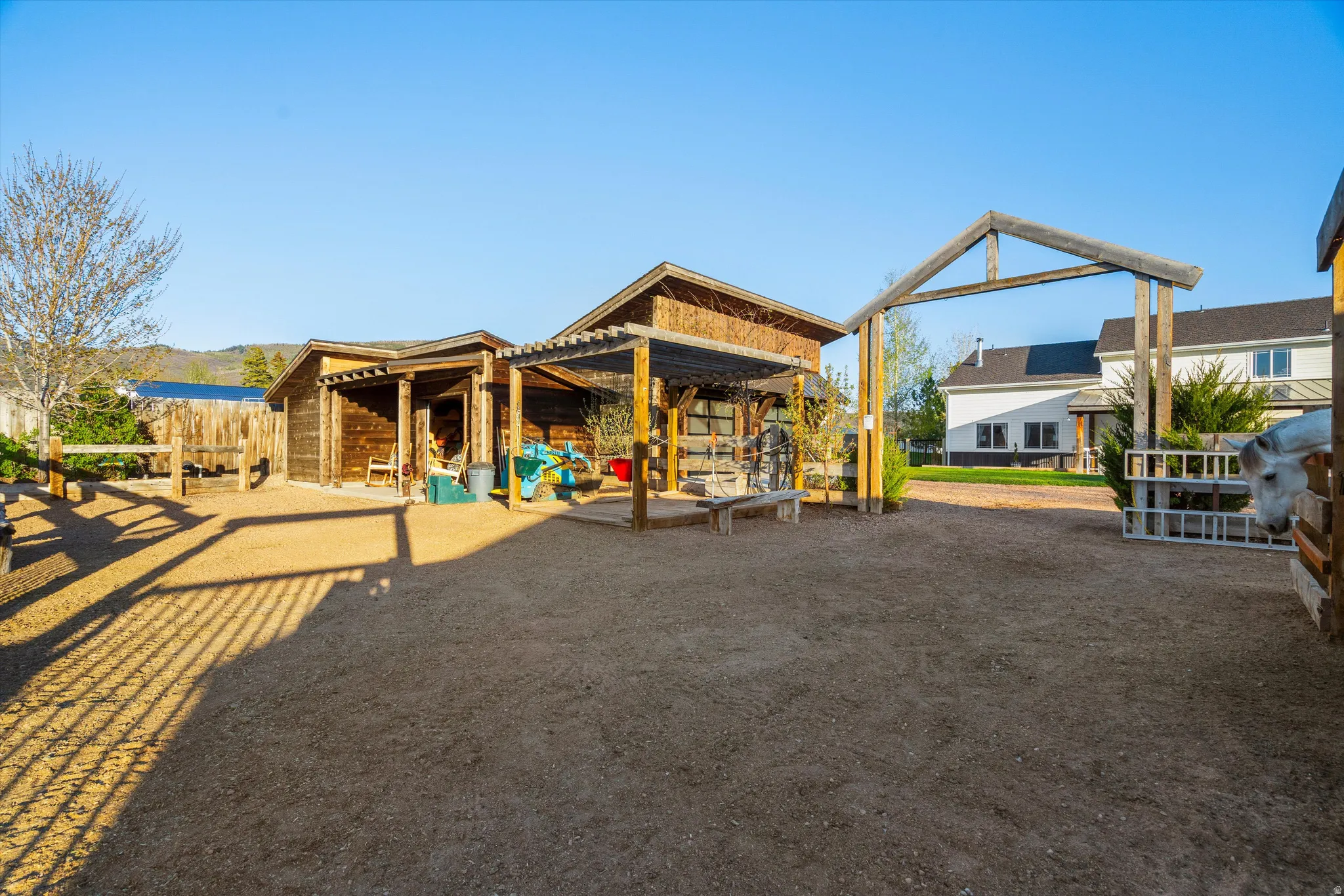 Gravel lot featuring multiple wood outbuildings, a wood pergola, and a decorative wood archway