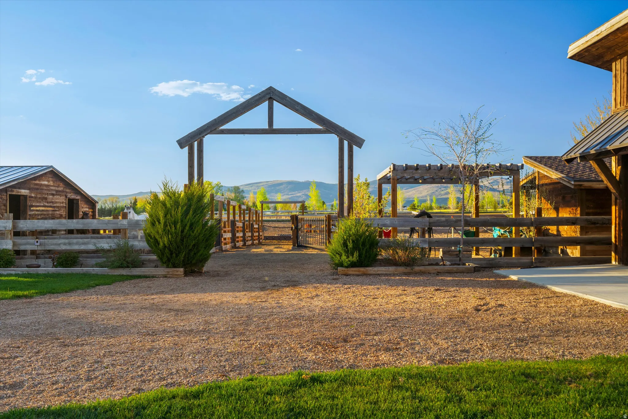 Expansive outdoor space featuring a gravel courtyard, verdant lawn, and a large wooden archway
