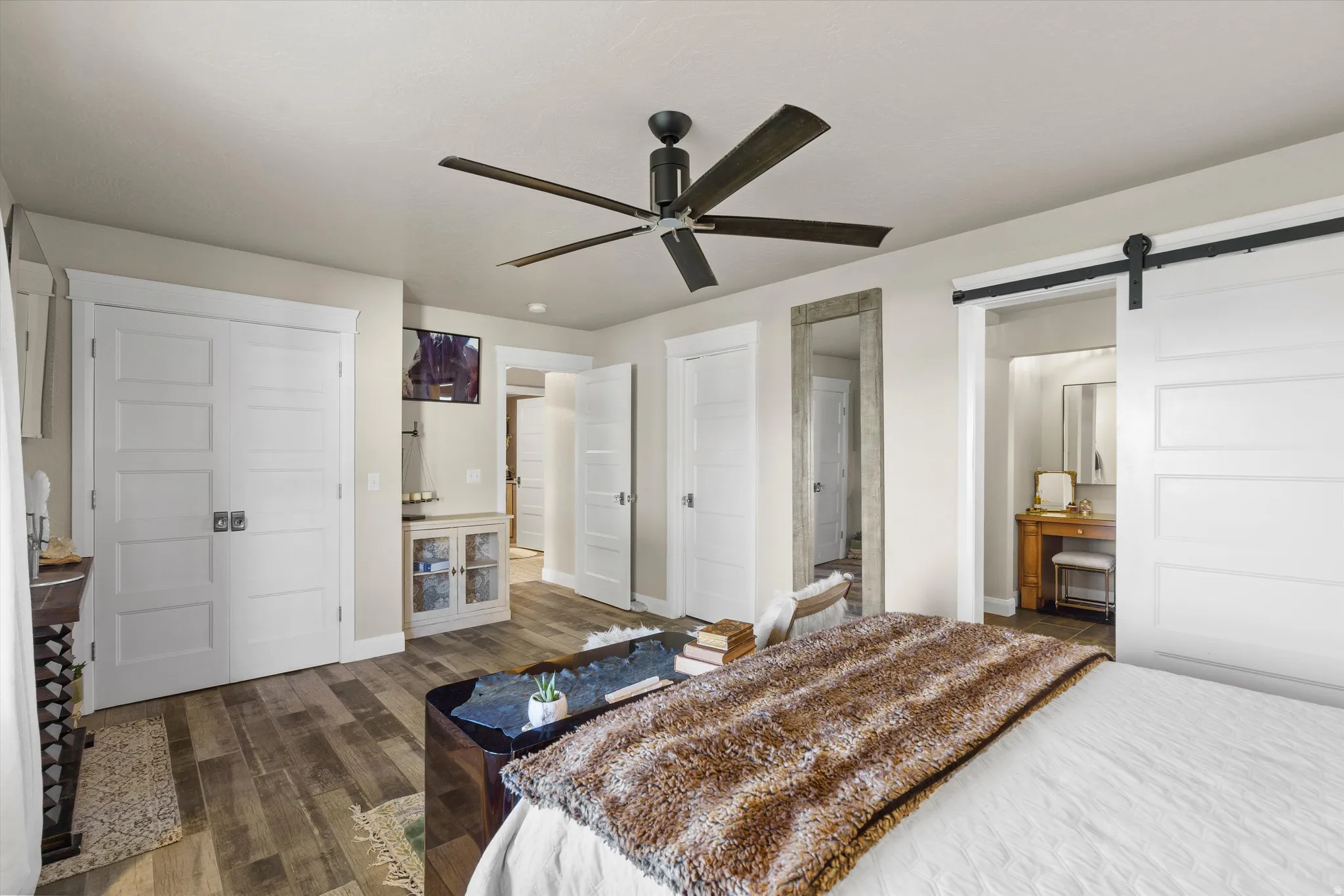 Spacious room featuring wood-finish flooring, a contemporary ceiling fan, and white five-panel doors