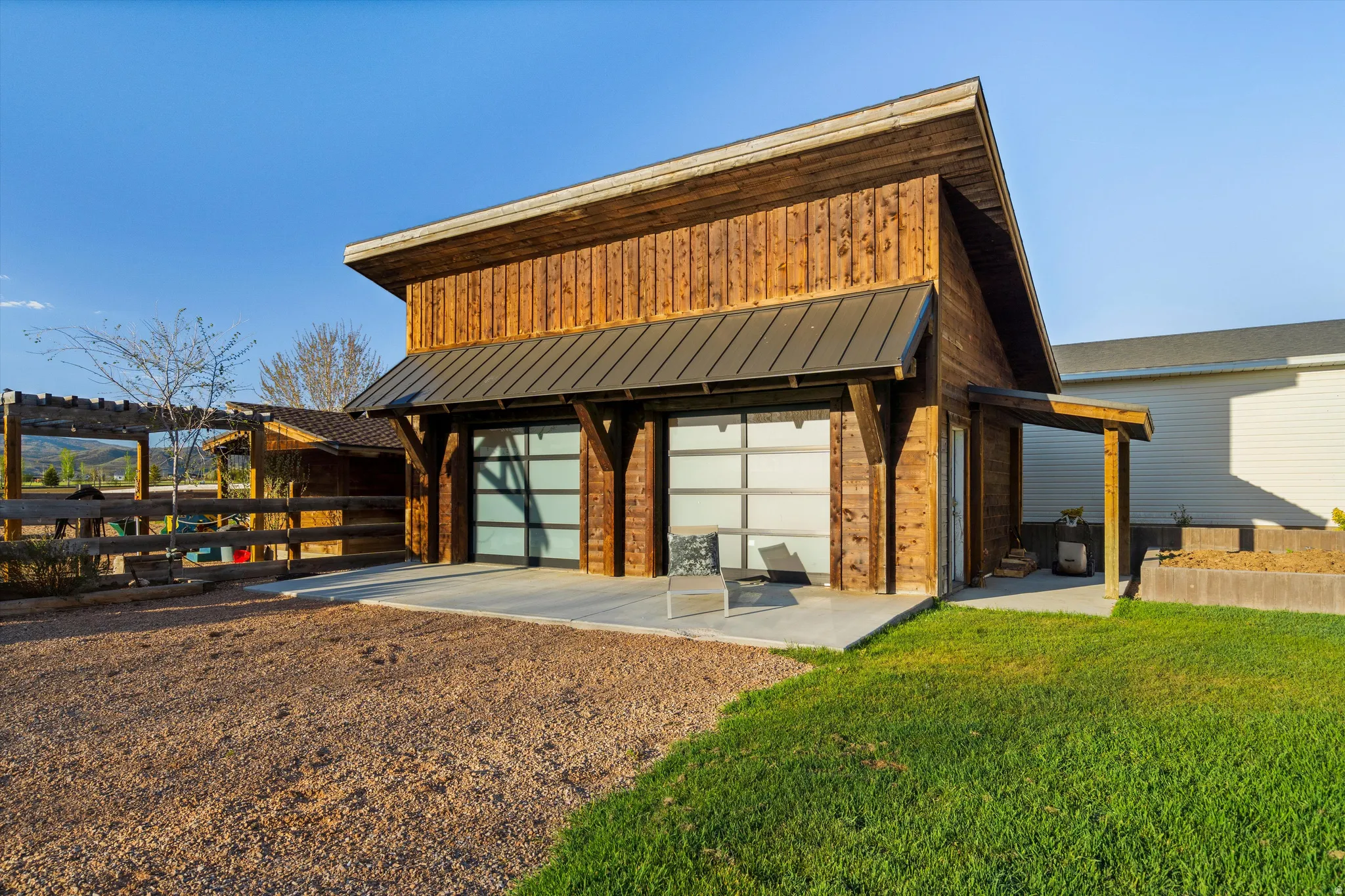 Modern barn-style structure featuring vertical wood siding, a standing seam metal roof, and two frosted glass overhead doors
