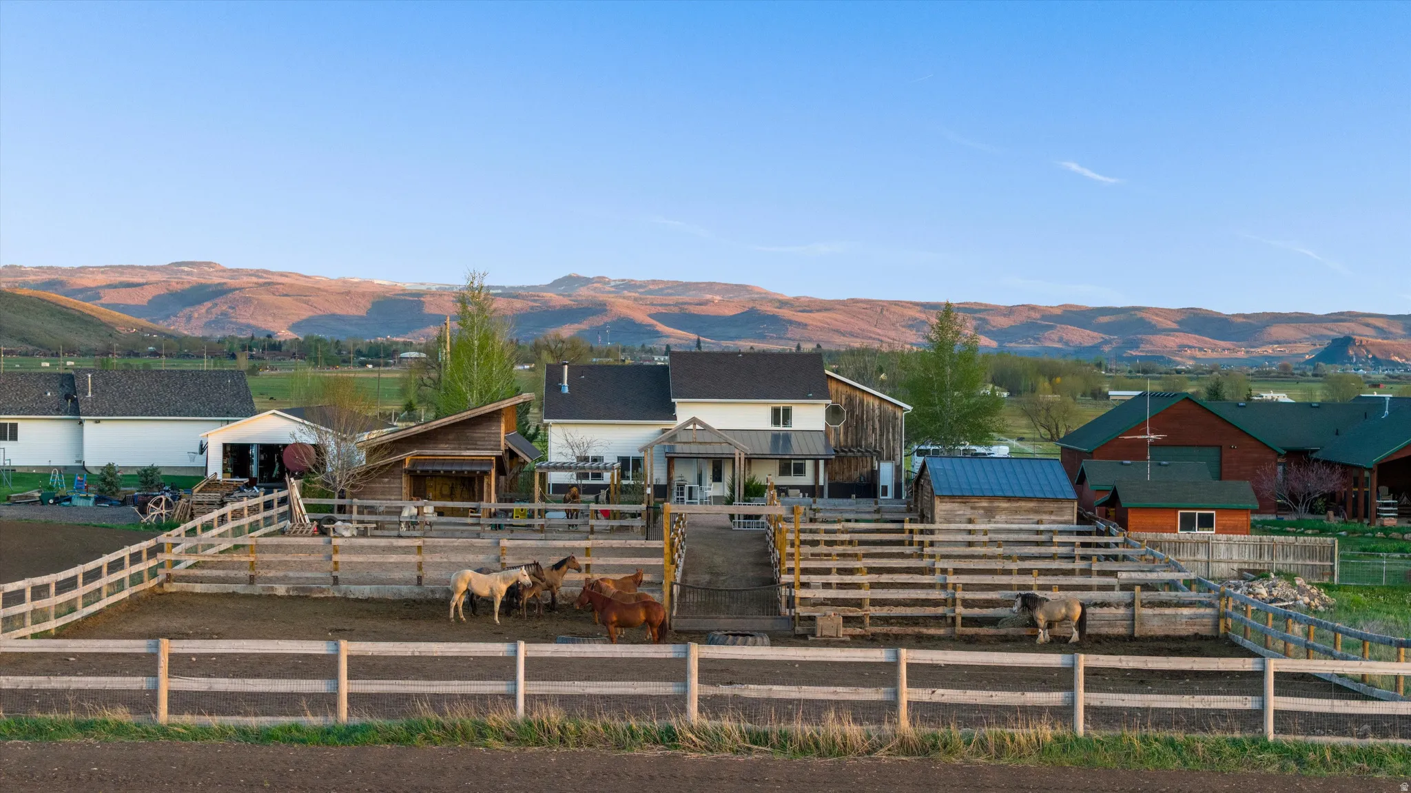 Expansive property featuring multiple fenced enclosures, surrounding a primary residence with an attached garage