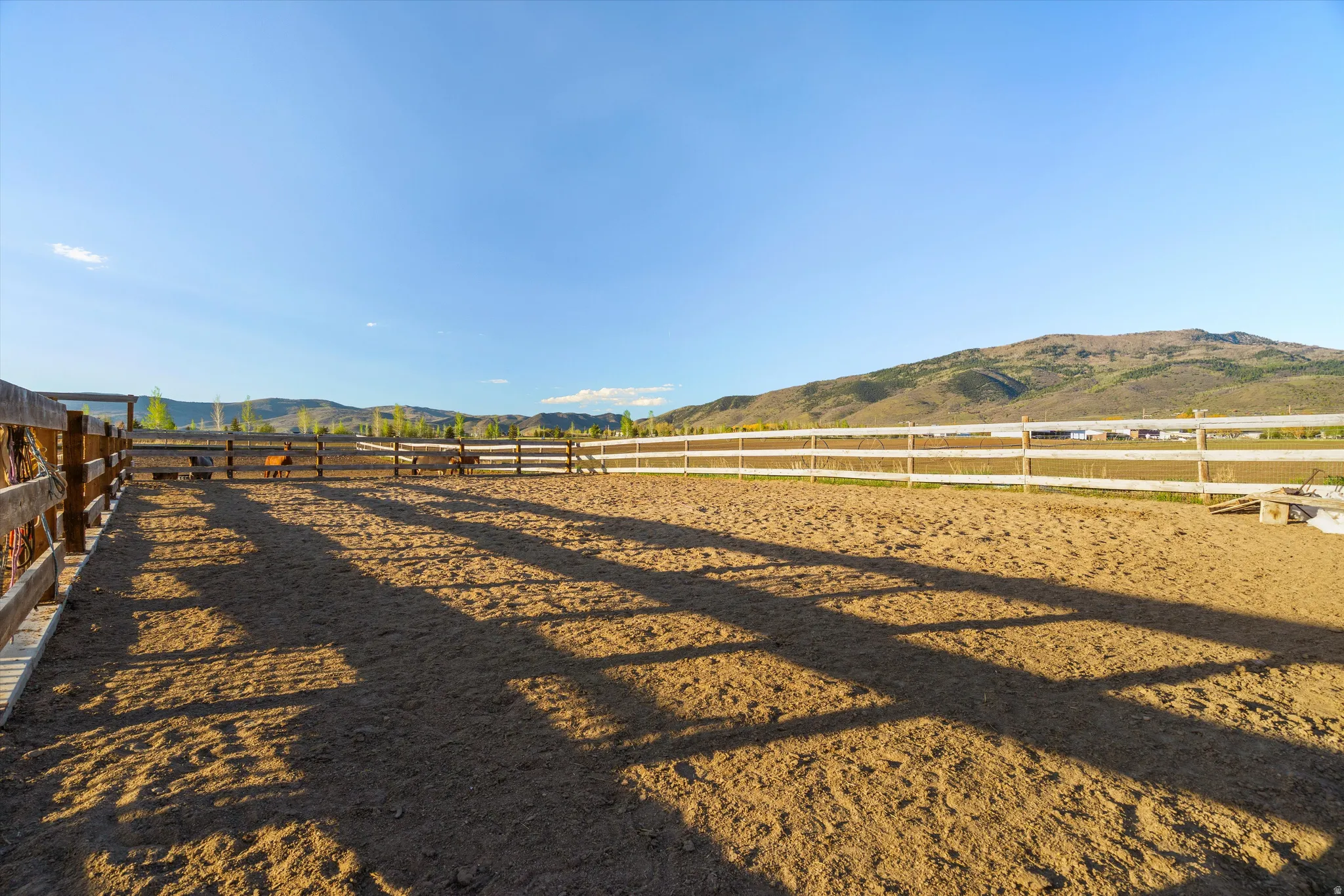 Expansive outdoor riding arena featuring a sand surface and perimeter fencing