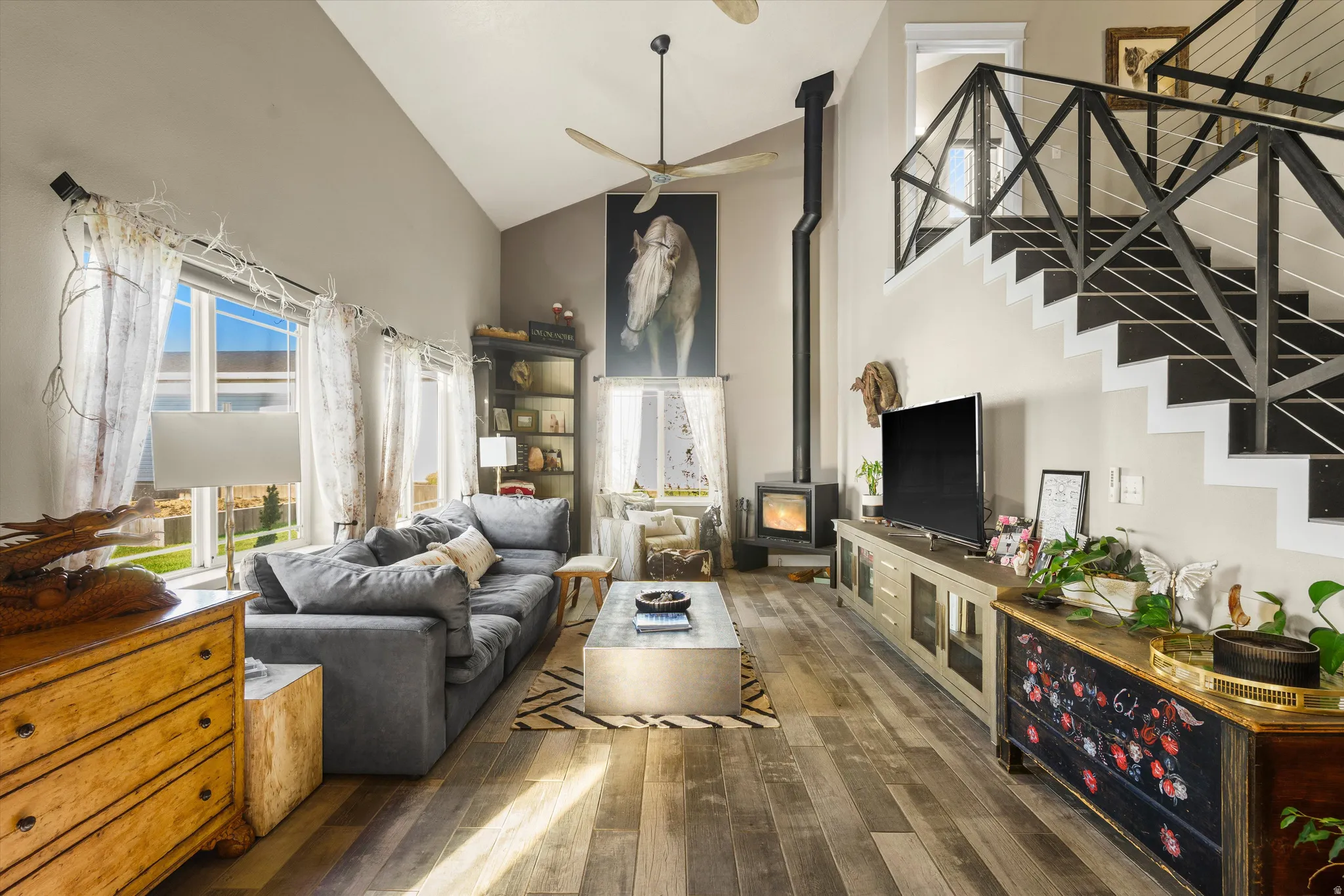 Great room featuring vaulted ceilings, wood-finish flooring, and a modern fireplace with a black flue