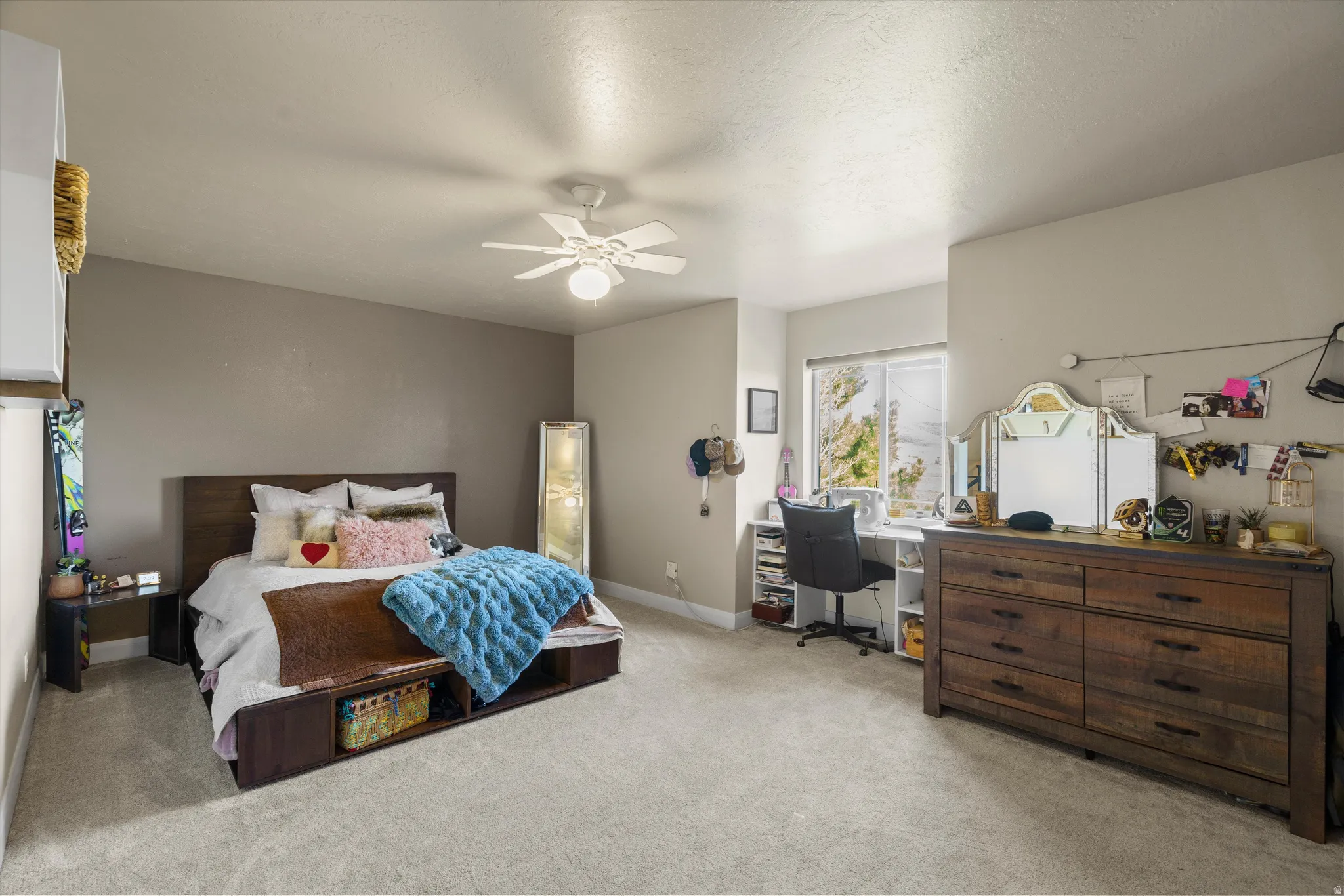 Carpeted room featuring neutral wall tones, a ceiling fan with integrated lighting, and a prominent window offering natural light