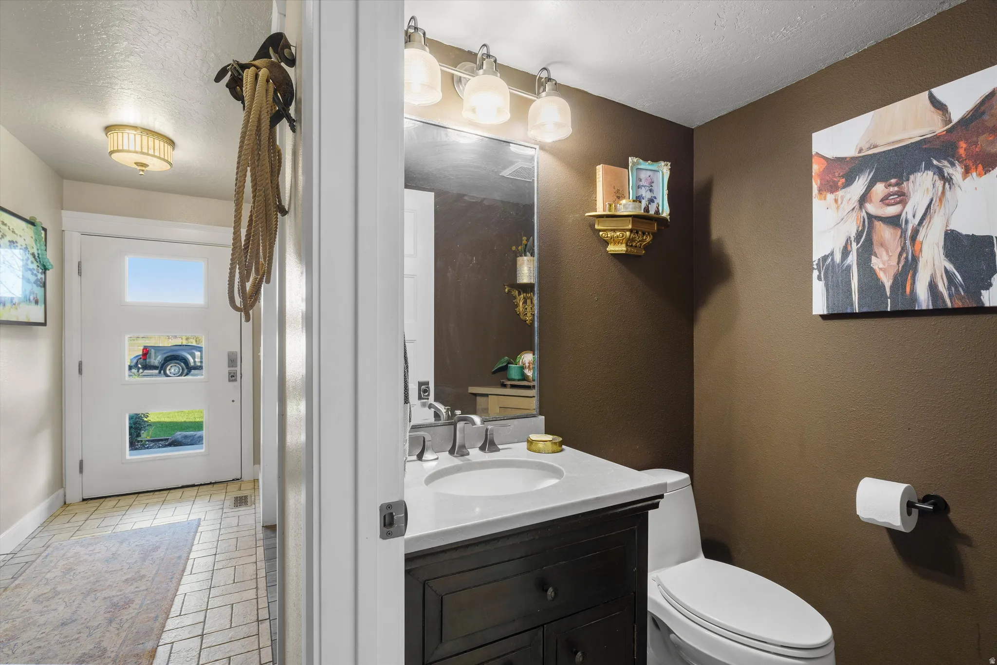 Powder room featuring a dark wood-finish vanity with a white countertop, chrome faucet, and bronze-toned walls
