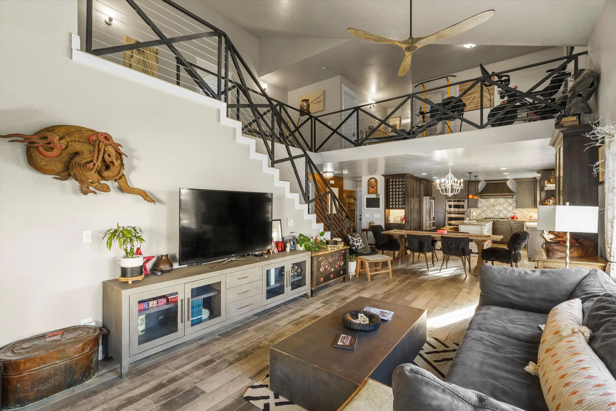 Open-concept living area with wood-finish flooring, a contemporary ceiling fan, and a built-in entertainment console