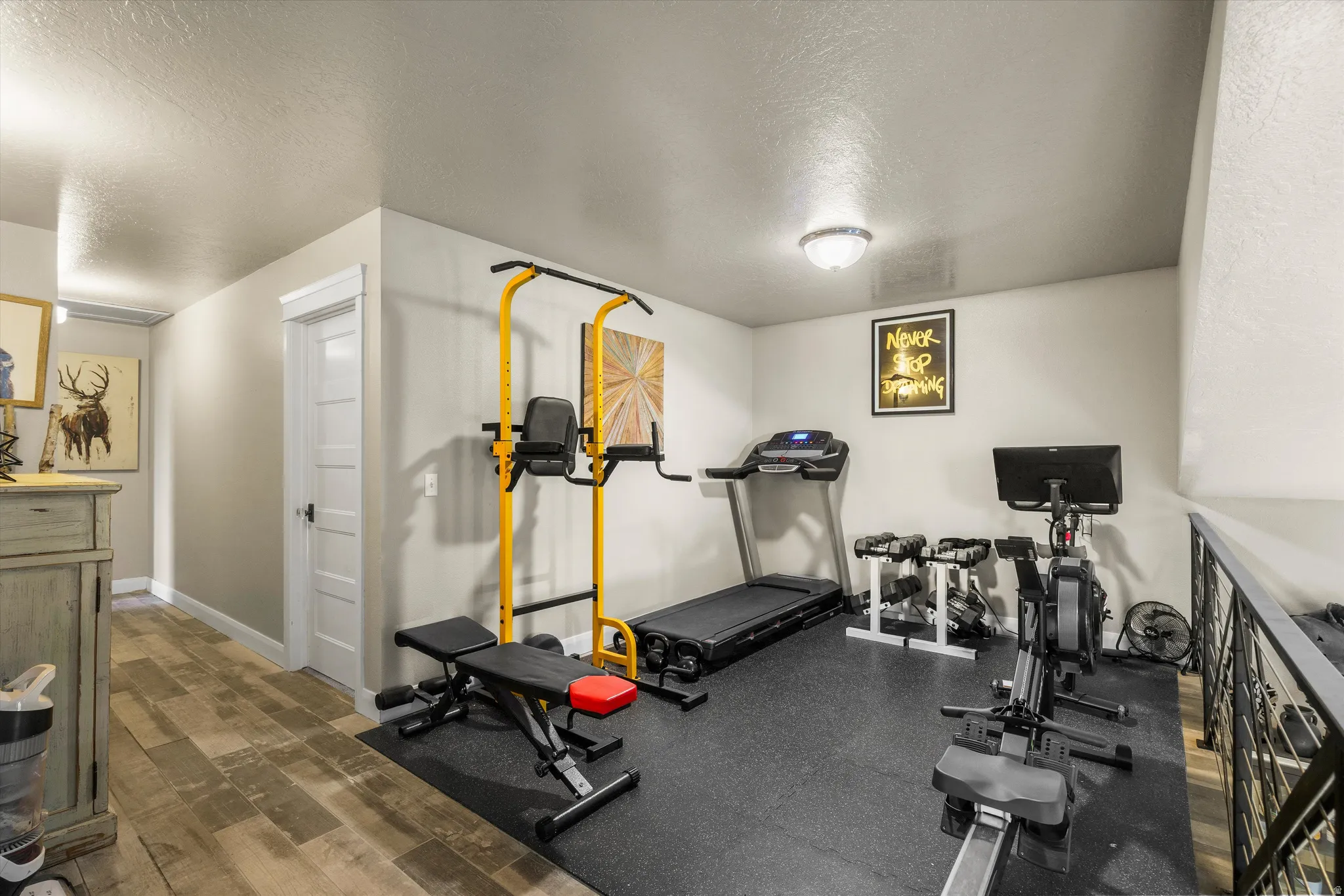 Dedicated fitness area featuring black rubber flooring, light gray walls, and recessed lighting