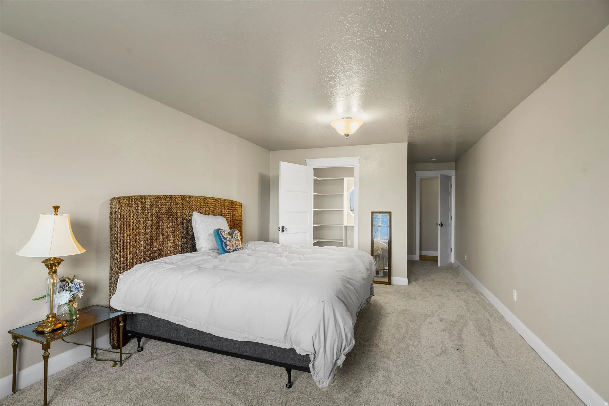 Carpeted room with neutral wall tones and a built-in closet with shelving