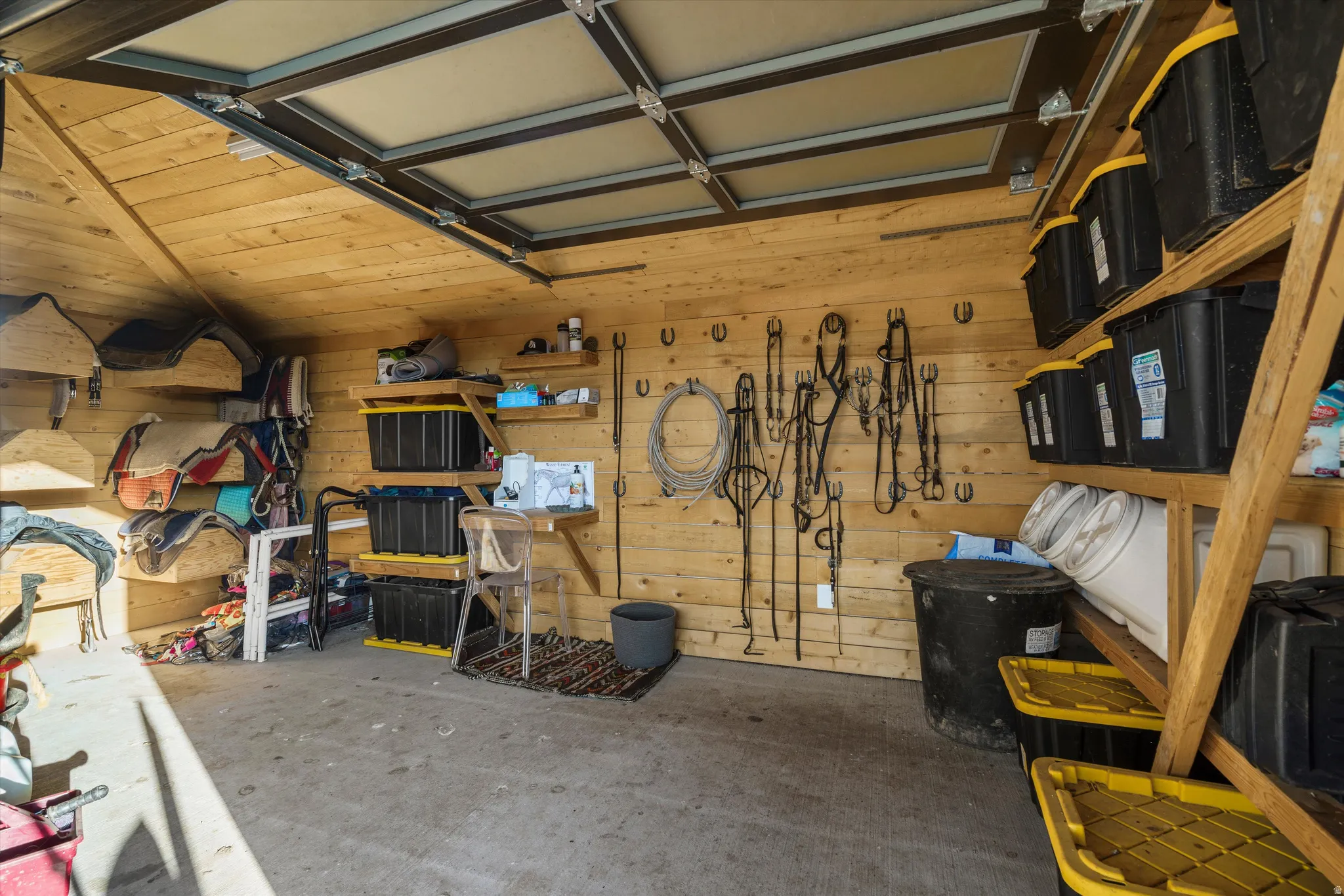 Utility structure interior featuring wood-finish wall paneling, a concrete floor, and an overhead garage door