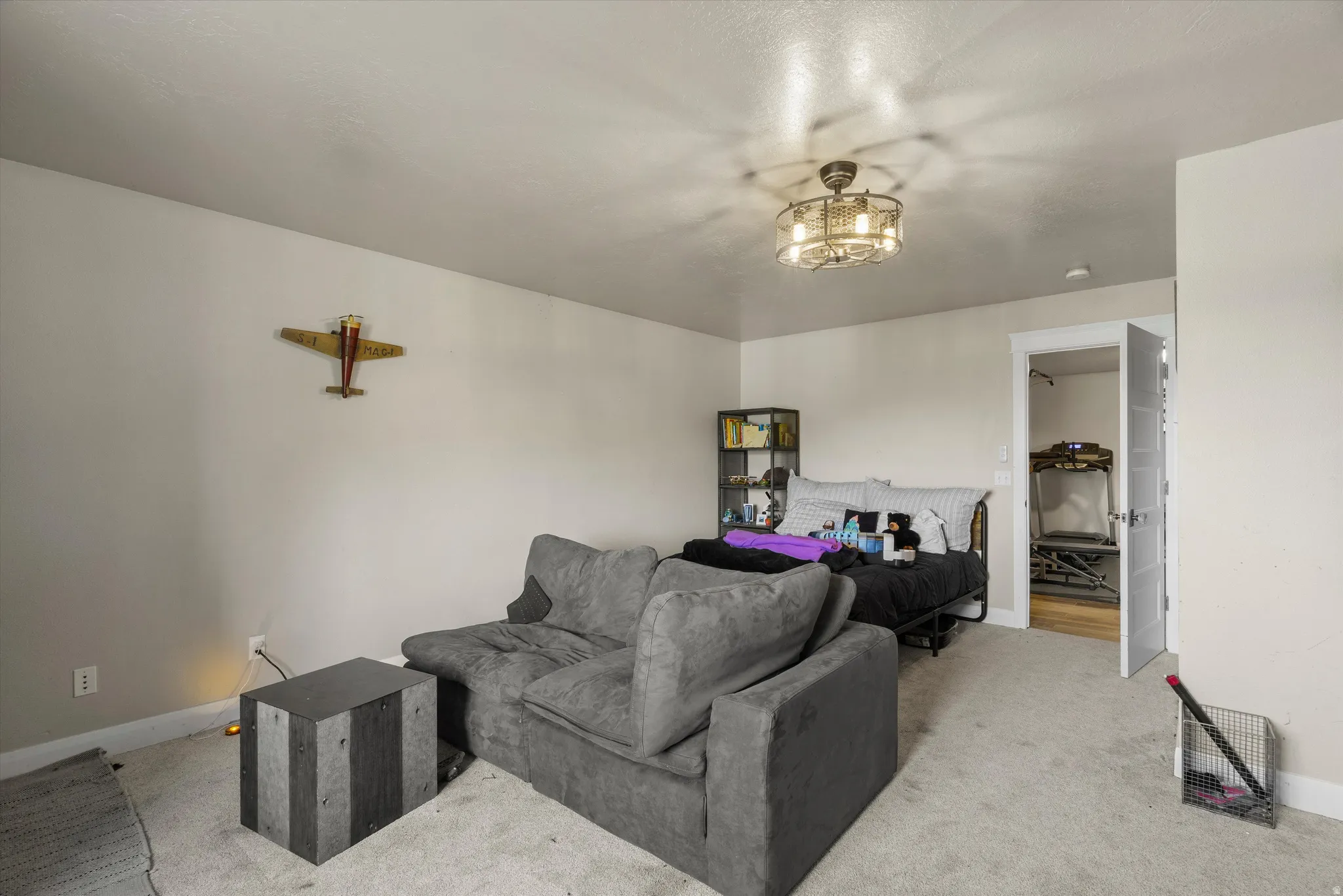 Carpeted room with a ceiling-mounted light fixture, light gray wall paint, white trim, and a paneled interior door