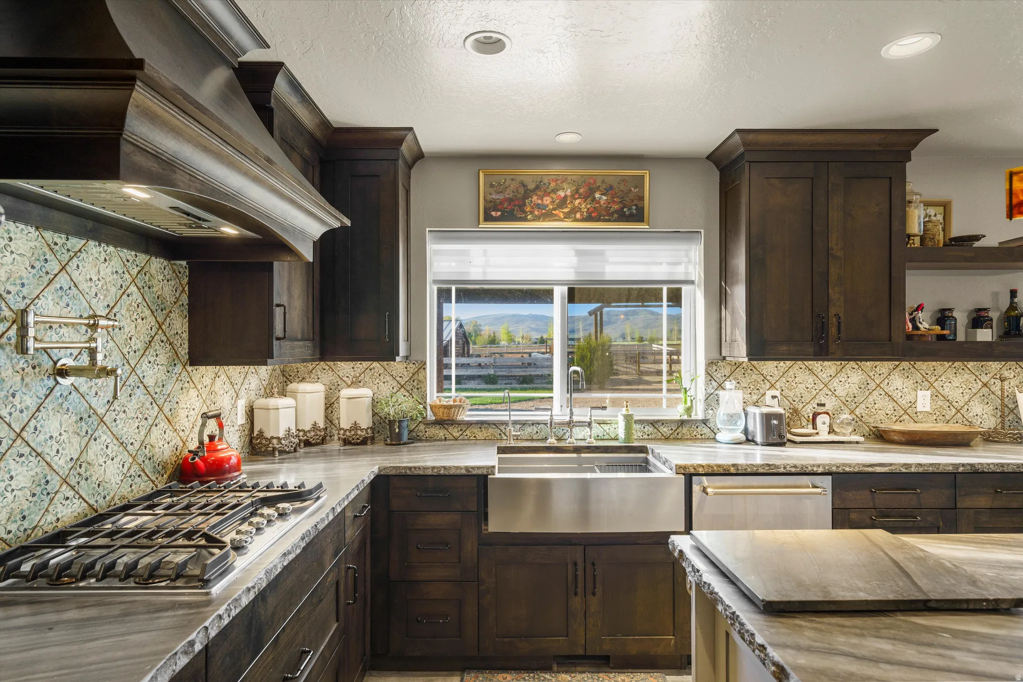 Gourmet kitchen featuring dark wood cabinetry, an industrial gas range with pot filler, stainless steel farmhouse sink, integrated dishwasher, and patterned tile backsplash