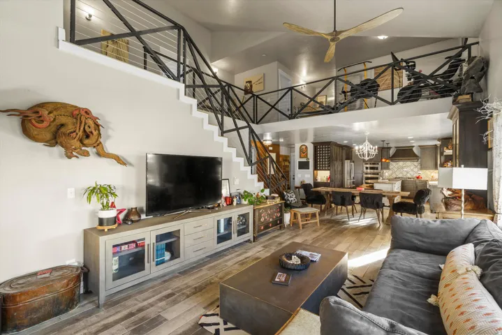 Open-concept living area with wood-finish flooring, a contemporary ceiling fan, and a built-in entertainment console