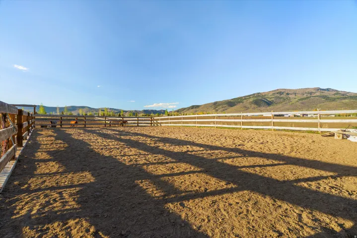 Expansive outdoor riding arena featuring a sand surface and perimeter fencing