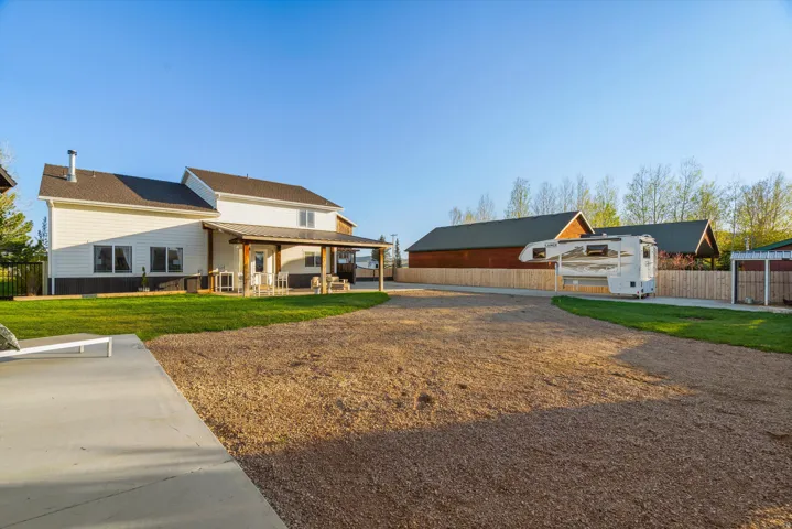 Spacious gravel driveway with an expansive rear patio, featuring a covered porch with wooden beams