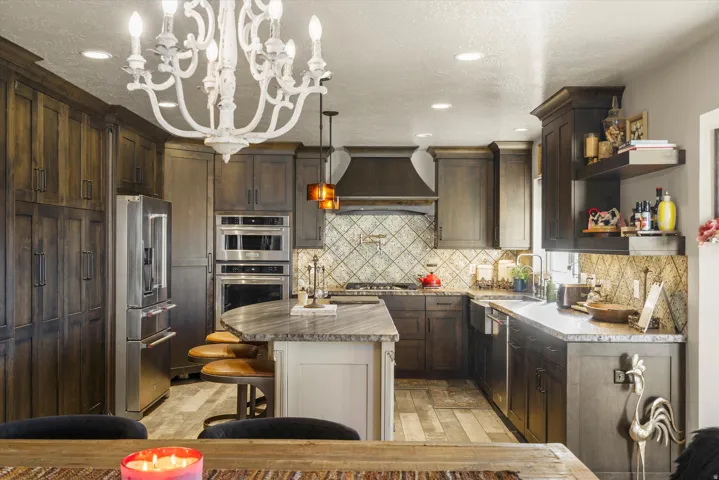 Spacious kitchen featuring dark wood-finish cabinetry, stainless steel appliances, and a central island with a stone-finish countertop