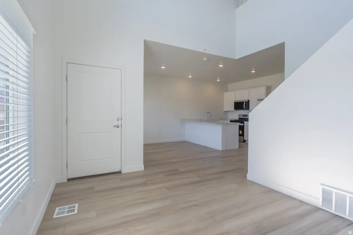 Open-concept layout with wood-finish flooring, recessed lighting, and a modern kitchen island with an undermount sink