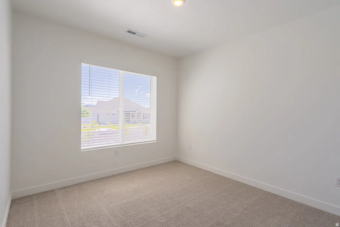Recessed ceiling light, neutral carpeting, window with blinds, and white walls