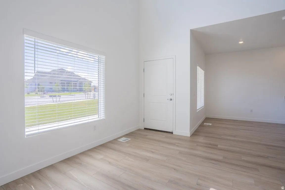 Vaulted ceilings with recessed lighting, wood-finish flooring, and a paneled entry door