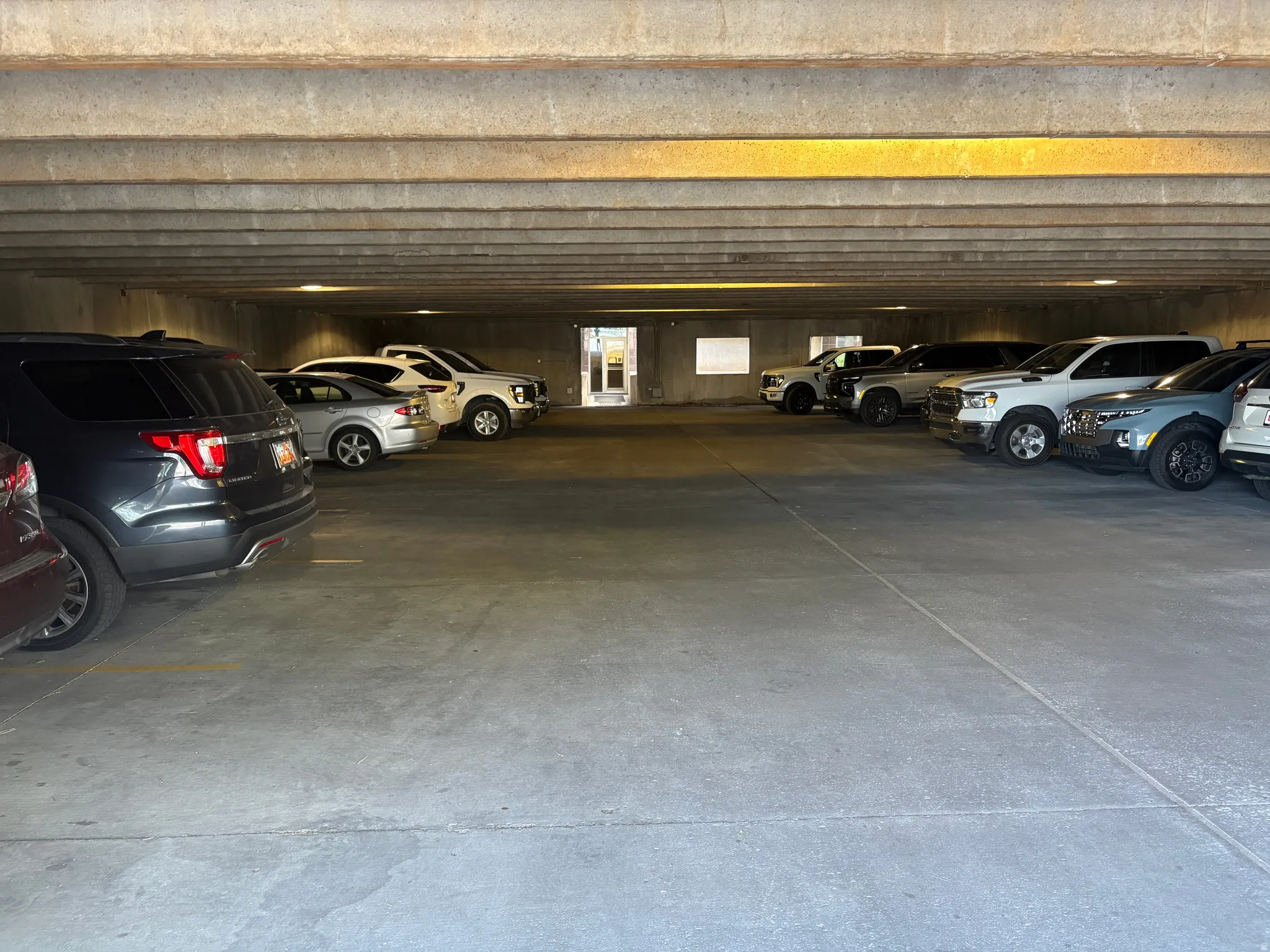 Enclosed concrete parking garage with overhead lighting and visible parking stalls