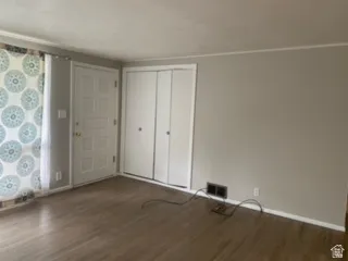 Entry area featuring wood-finish flooring, a paneled door with brass hardware, and bi-fold closet doors