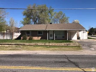 Ranch-style residence featuring a brown shingle roof and a carport