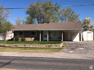 Single-story residence featuring a brown shingle roof, tan brick exterior, and a covered carport