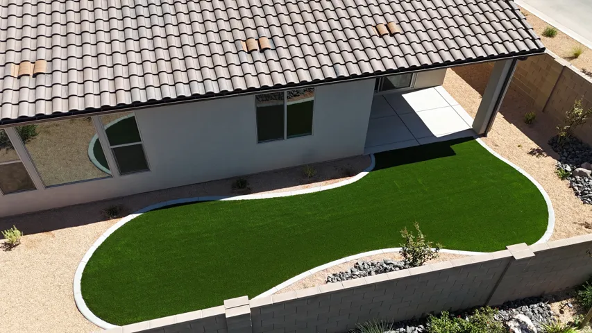 Terracotta tile roofing, stucco exterior, covered patio, artificial turf lawn, and gravel landscaping