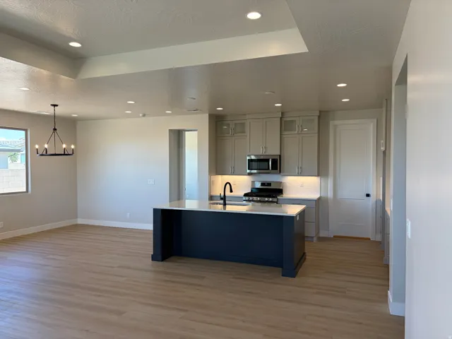 Open-concept living space featuring wood-finish flooring, recessed lighting, and a tray ceiling