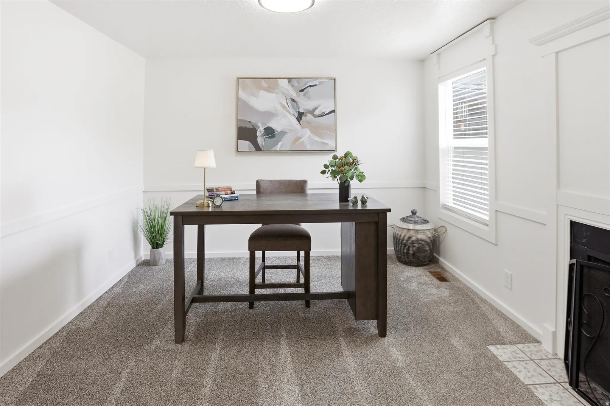 Carpeted room featuring white walls, chair rail molding, a window with blinds, and a built-in fireplace with a tiled hearth