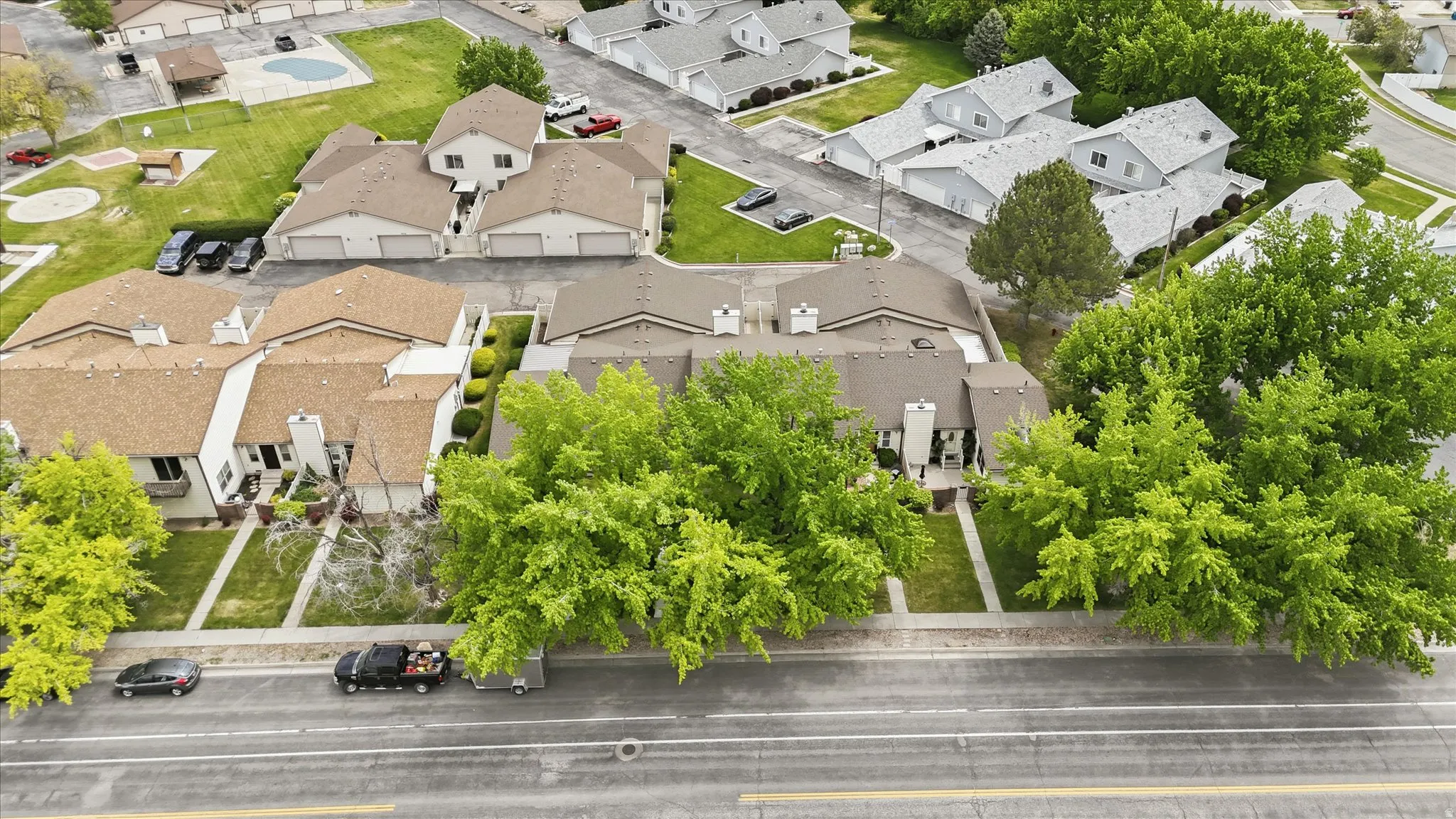 Aerial depiction of a residential community featuring townhomes with brown shingle roofing and light-colored facades