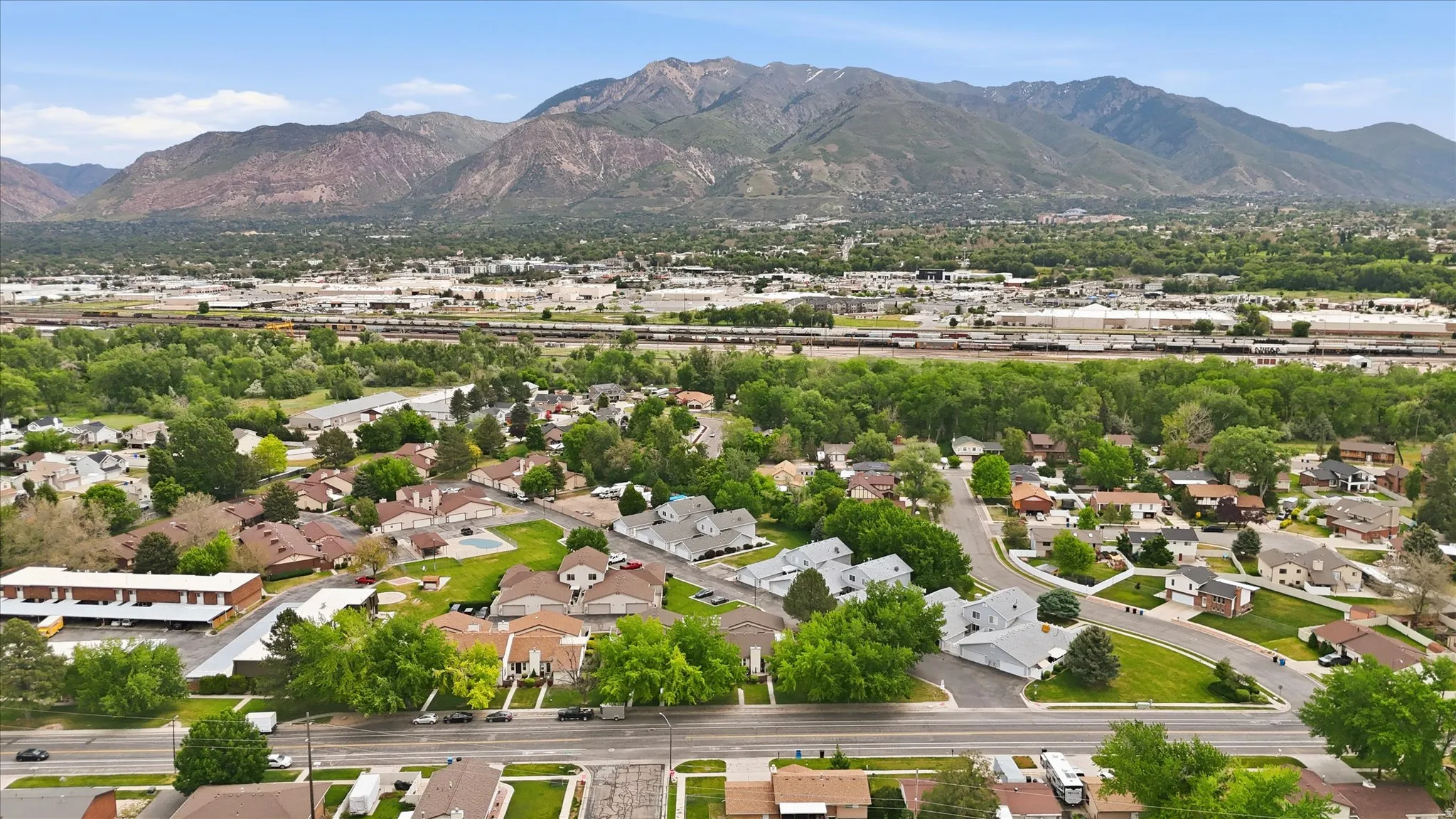 Aerial perspective showcasing a residential area with mature trees and mountain ranges in the background