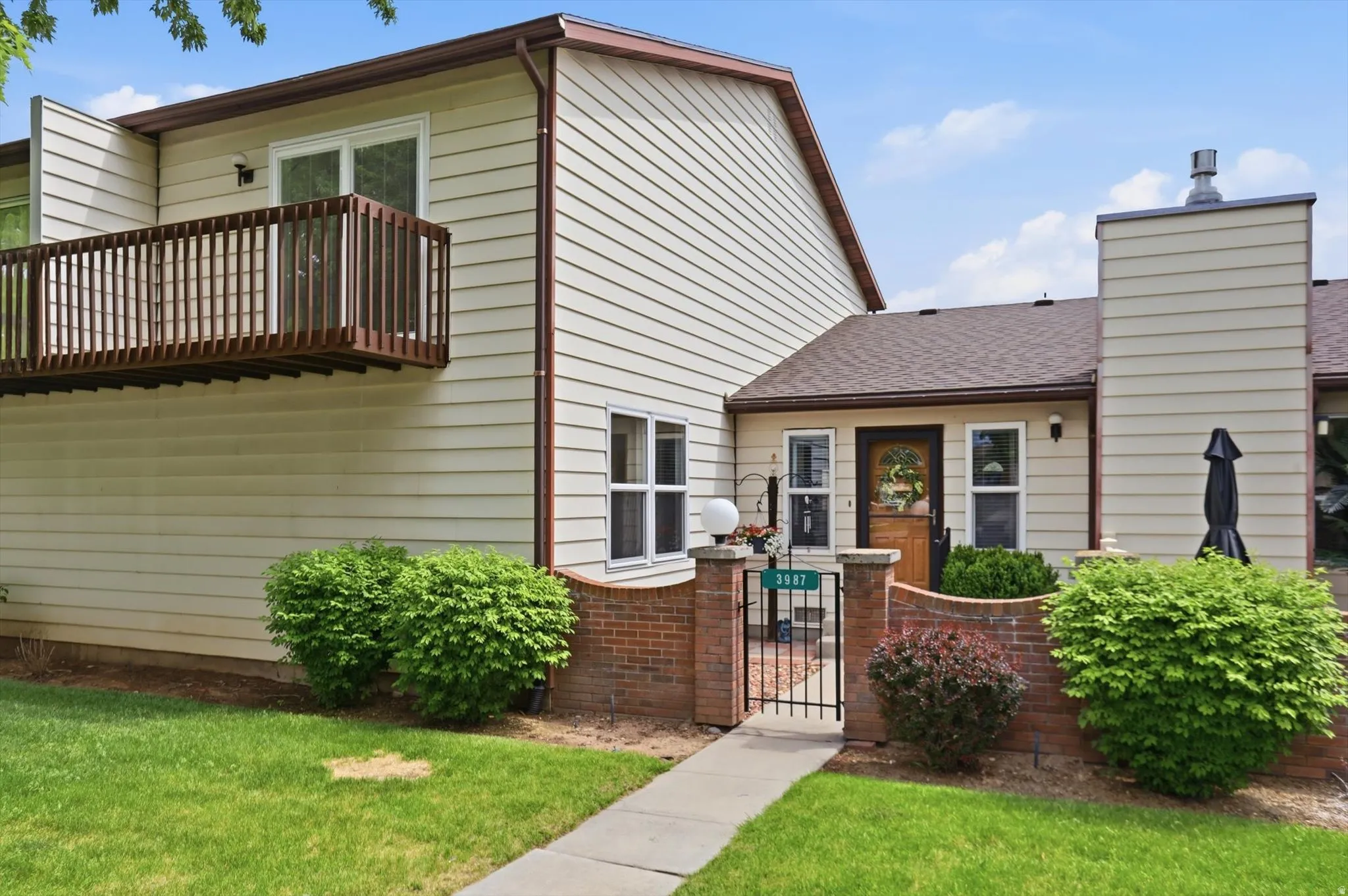 Exterior featuring light-colored horizontal siding, a private balcony with wood railing, and a gabled roof