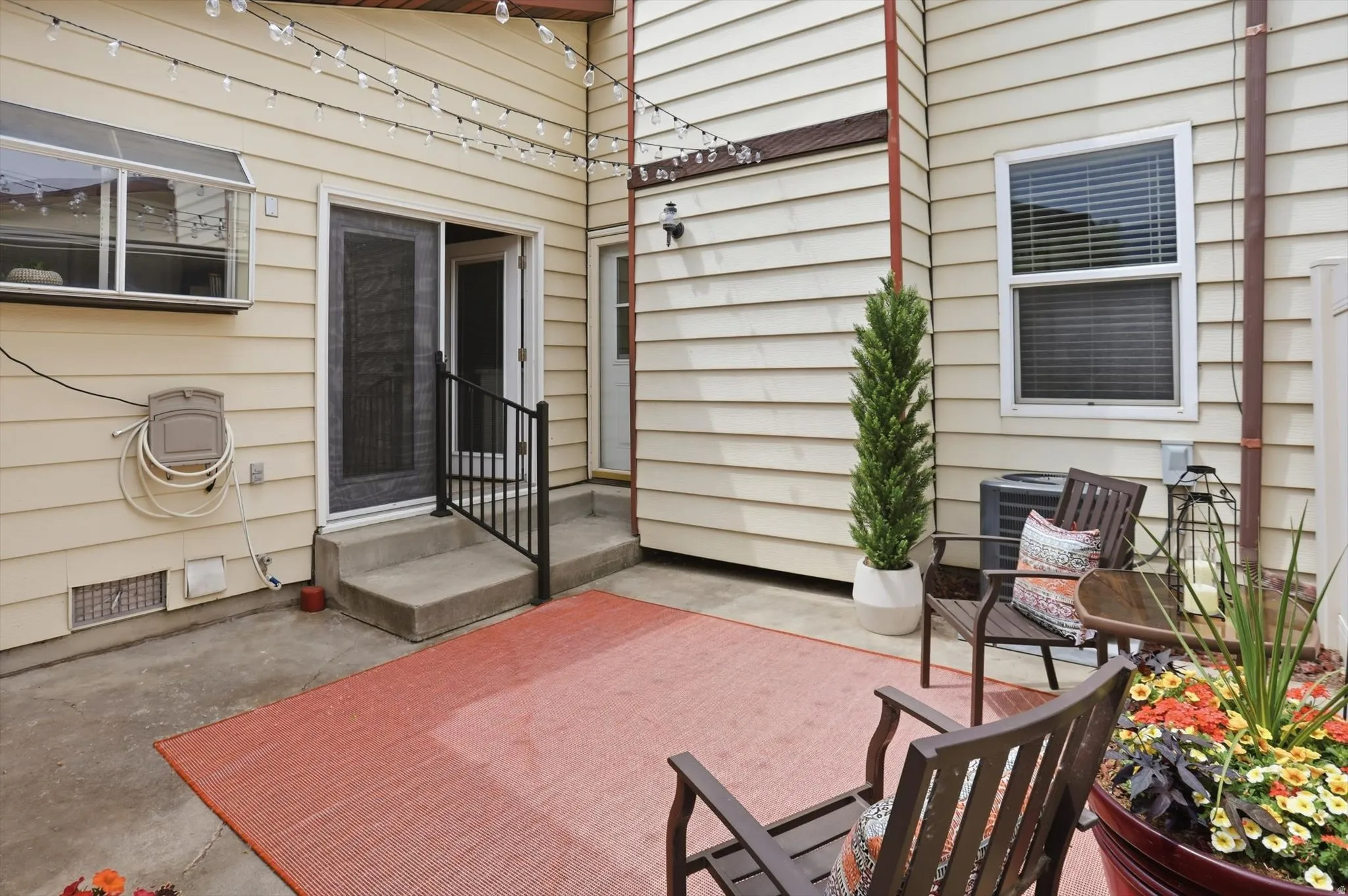 Concrete patio area featuring a sliding glass door with screen, a secondary entry door, and exterior wall siding