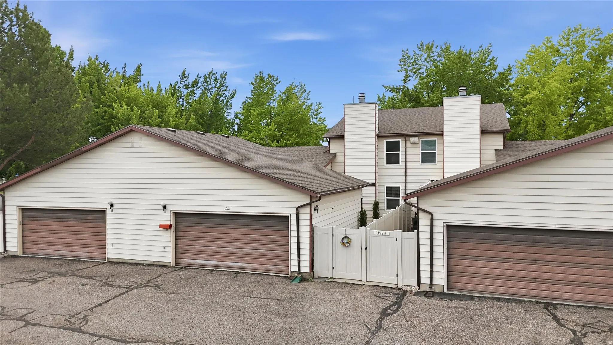 Exterior featuring white siding, brown wood-finish garage doors, and a white privacy fence