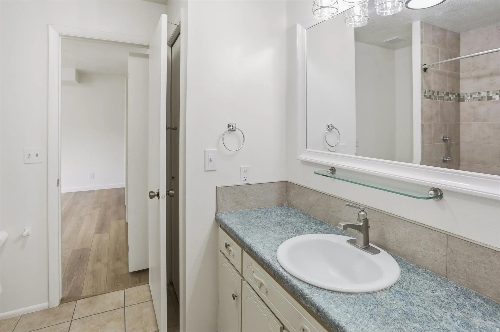 Bathroom vanity featuring an oval undermount sink with brushed nickel faucet, a speckled countertop, and white cabinetry
