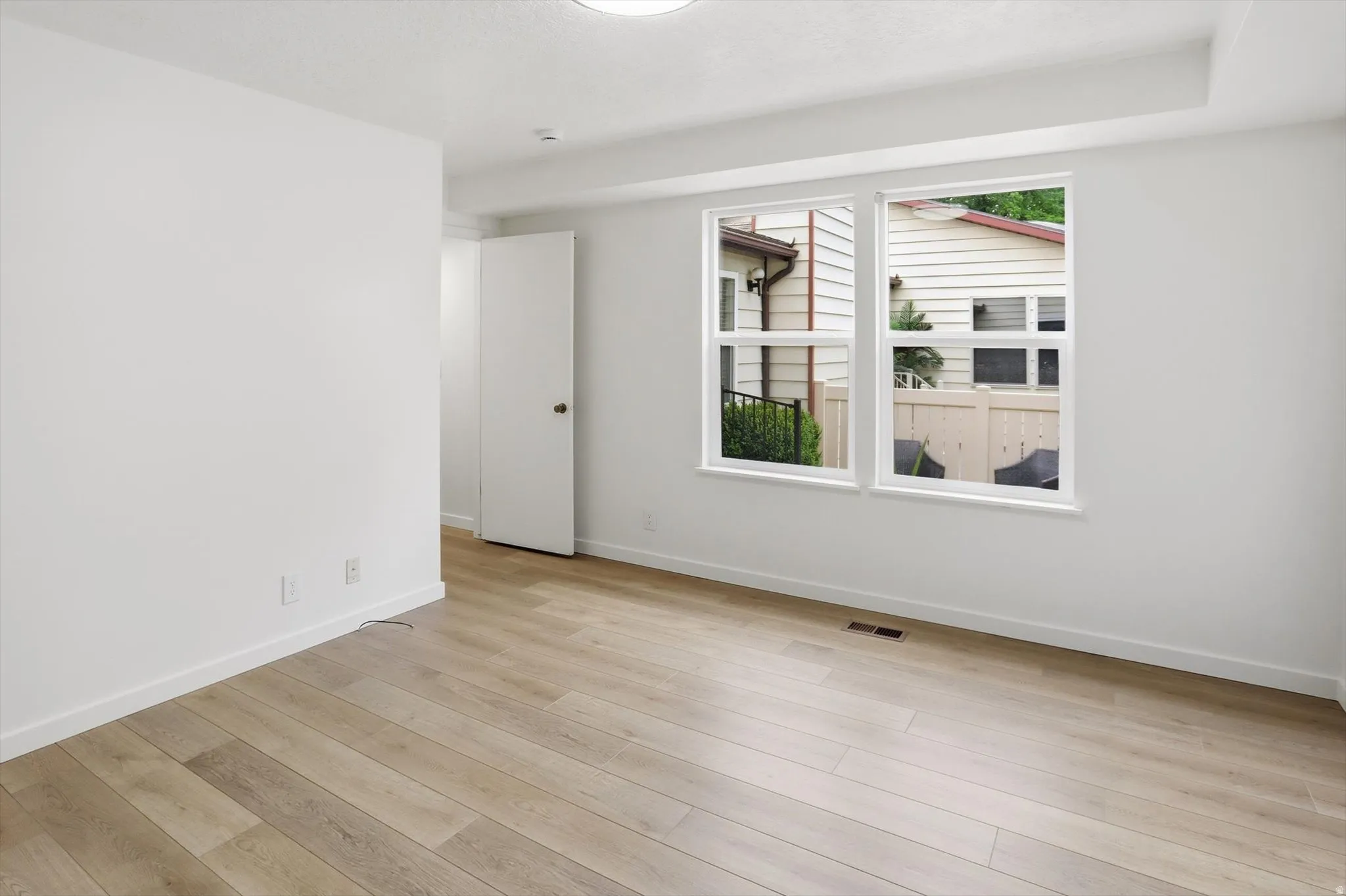 Bright room featuring wood-finish flooring, white walls, and a pair of windows