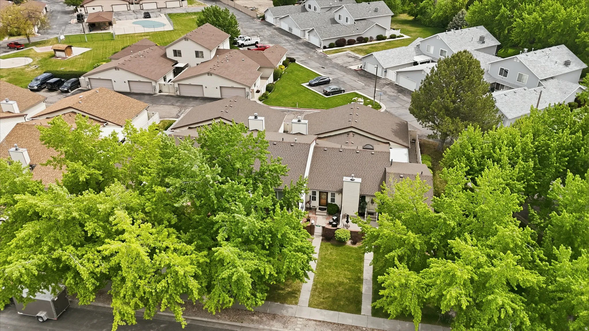 Aerial view showcasing a residential community with mature trees and a manicured lawn