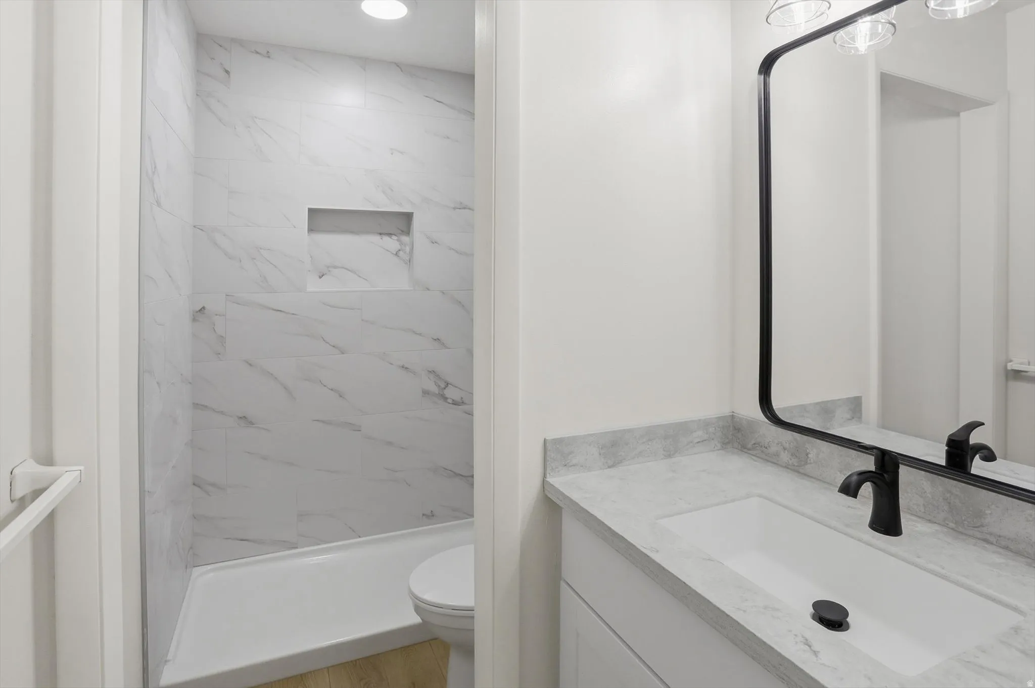 Bathroom featuring a vanity with an integrated sink, a dark-toned faucet, and a large framed mirror