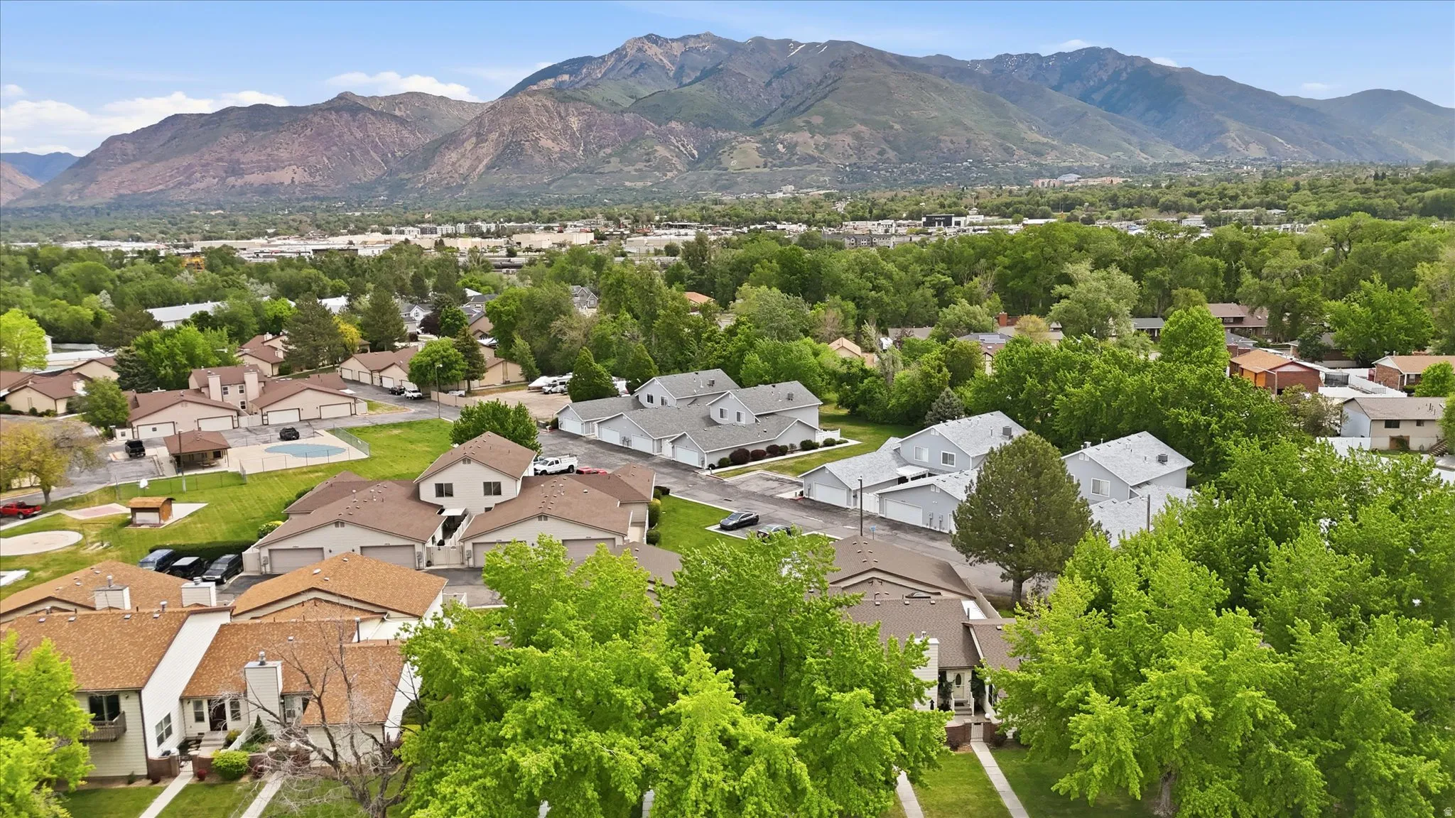 Neighborhood aerial featuring a mountainous backdrop, mature trees, and residential properties with various rooflines